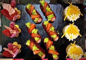 Fototapeta premium sushis and desserts placed on a black iron board 