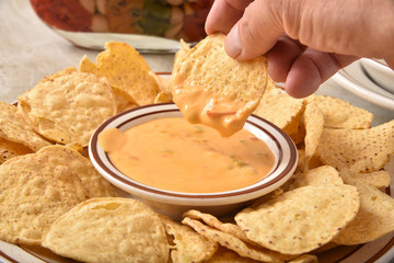 Dipping a tortilla chip in cheese sauce