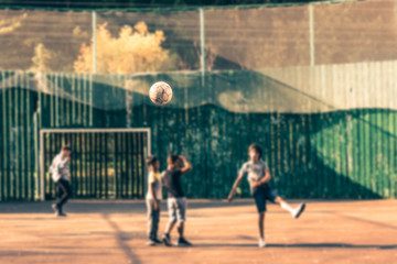 Fototapeta na wymiar Boys are play football in the yard sports ground. Focus on the flying ball