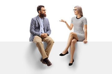Young woman having a conversation with a bearded man while sitting on a panel