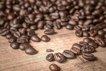 Coffee on wooden background. Brown roasted coffee beans, seed on dark background. Espresso dark, aroma, black caffeine drink. Closeup isolated energy mocha, cappuccino ingredient.