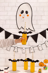 Woman holding creative yellow pumpkin drink with bat