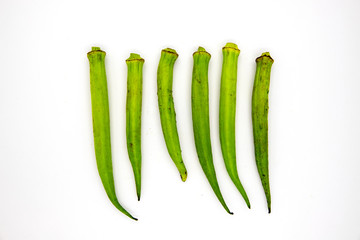 Green bamia in row on white background. Tropical vegetable top view photo. Exotic plant with edible green pod.