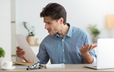 Discontented Guy Reading Tax Notification Sitting At Laptop In Office