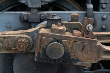 Industrial or transportation or steam punk vintage background with detail of old rusty steam locomotive featuring crank mechanism, frame, wheels and suspension system. 