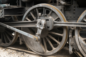 Industrial or transportation or steam punk vintage background with detail of old rusty steam locomotive featuring crank mechanism, frame and  wheels. 