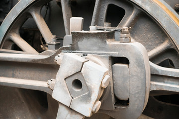 Industrial or transportation or steam punk vintage background with detail of old rusty steam locomotive featuring crank mechanism, frame and  wheels. 