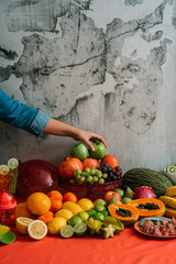 Woman's hands taking up a green apple from a table with a great variety of fresh organic fruits and...