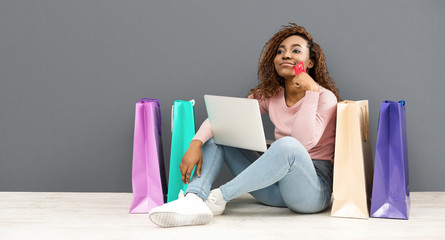 Dreamy girl with credit card making shopping using laptop