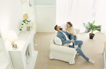 Millennial couple resting on sofa in light interior room