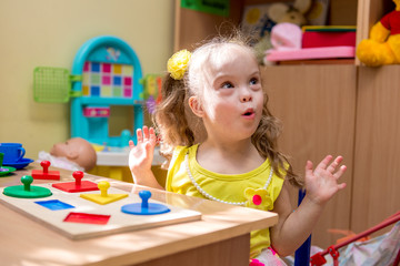 Girl with down syndrom developing motor skills in rehab center for special children