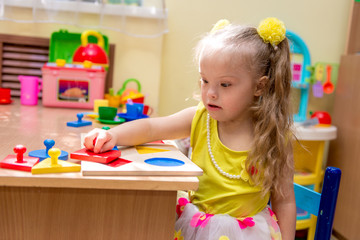 Girl with down syndrom developing motor skills in rehab center for special children