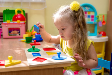 Girl with down syndrom developing motor skills in rehab center for special children