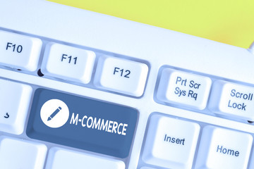 Writing note showing M Commerce. Business concept for commercial transactions conducted electronically by mobile phone White pc keyboard with note paper above the white background