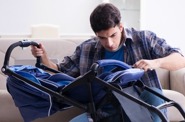 Young father assembling baby pram at home