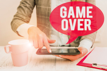 Fototapeta na wymiar Text sign showing Game Over. Business photo showcasing A situation in a particular sport that reach his finals or ending Business woman sitting with mobile phone and cup of coffee on the table