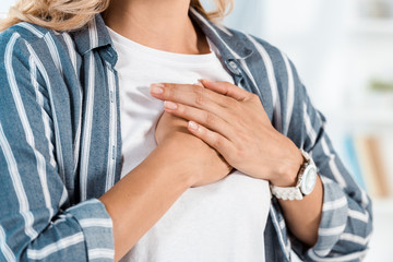 cropped view of woman touching chest at home