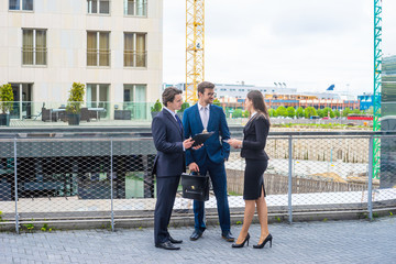 Confident businesspersons talking in front of modern office building. Businessman and businesswoman have business conversation. Banking, professional job and financial market.