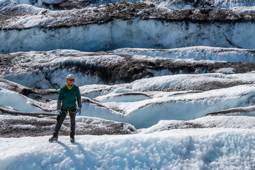 Man standing on a rib of white ice among many crevasses on the Matanuska Glacier.