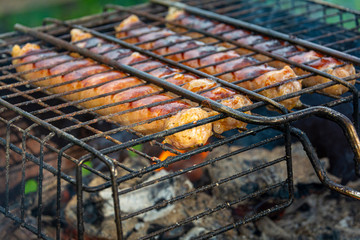 Grilled Sausages On The Grill. Grilled sausages. Cooking in the fresh air. Concept: outdoor recreation, delicious, natural food, relaxation and entertainment.