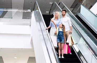 Girl Showing Something To Parents Standing On Escalator In Hypermarket