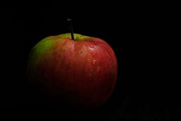 drops of water on a red-green apple. Black background