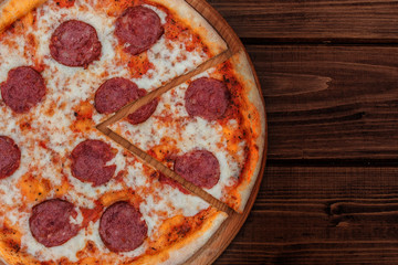 Italian Pepperoni pizza with salami on dark wooden background top view. Italian traditional food. Popular street food