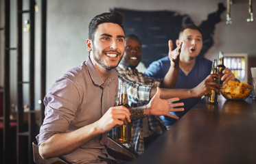 Football fans watching match in sport bar, drinking beer