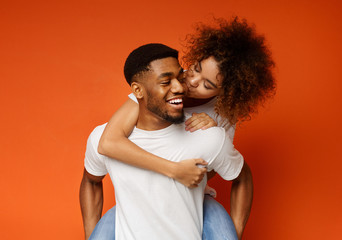 African american millennial couple fooling together, girl kissing her boyfriend