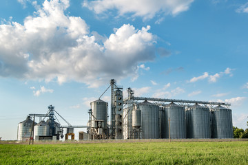 Obraz premium agro-processing plant for processing and silos for drying cleaning and storage of agricultural products, flour, cereals and grain with beautiful clouds
