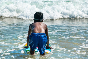 A young boy readies himself for some bodyboarding as he ventures into the waves