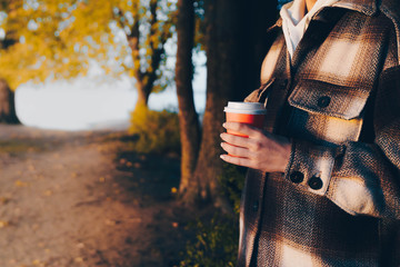 woman holding coffee for take away in autumn. paper cup coffee on the go. fall concept.