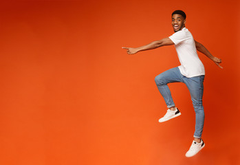 Fototapeta na wymiar Excited african american guy walking in air