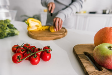 selective focus of cherry tomatoes near apple and woman