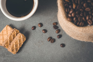 Cup of coffee with some cookies and coffee beans in jute sack..