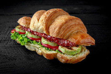 Vegetarian Croissant sandwich with grilled vegetables: zucchini, peppers, sun-dried tomatoes, lettuce and sauce. Healthy, tasty, nourishing snack. Take away food