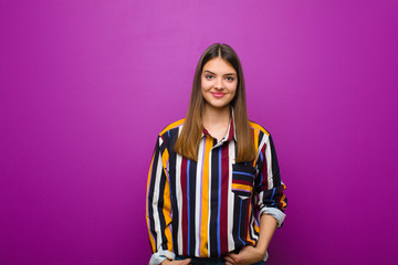 young pretty woman looking proud, confident, cool, cheeky and arrogant, smiling, feeling successful...