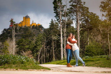 Two friends hugging in front of Pena Palace in Sintra, Portugal - obrazy, fototapety, plakaty