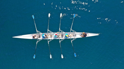 Naklejka premium Aerial top down photo of sport canoe operated by team of young men in open ocean deep blue sea