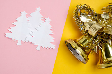 Christmas trees made of white paper with golden Christmas bells on soft paper whatman are pink and yellow.