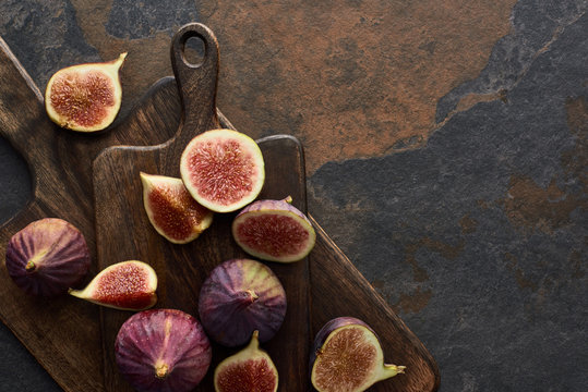 top view of ripe whole and cut delicious figs and cutting boards on stone background