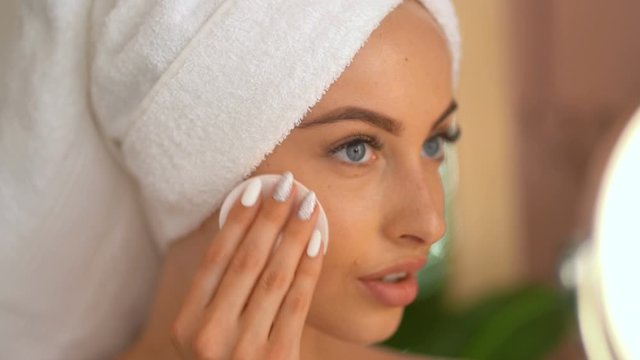 Woman removing makeup from her face in modern bathroom