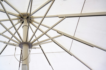Large market or gastronomy parasol with white fabric and metal struts, which are opened by motor...