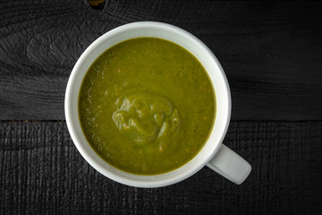 Cream soup made of pumpkin, spinach, broccoli and lentils with parmesan, pumpkin seeds and cream. Tasty, healthy nutritious lunch.