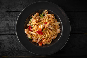Seafood spaghetti pasta: mussels, shrimps in a dark plate on black boards
