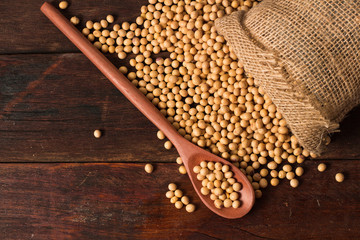 Fresh an raw soy beans in rustic fabric bag on wooden table.
