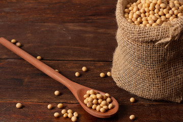 Fresh an raw soy beans in rustic fabric bag on wooden table.