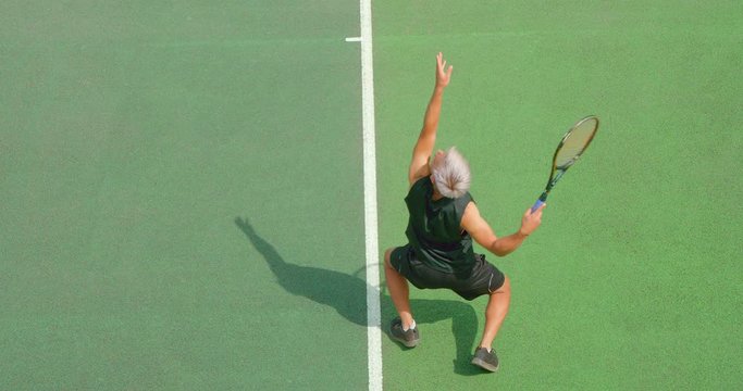 A mixed race tennis player with platinum blond hair servesserves 