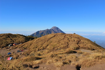 beautiful blue skies and brownish grasslands on a clear morning while climbing Mount Merbabu Magelang, Central Java, Indonesia