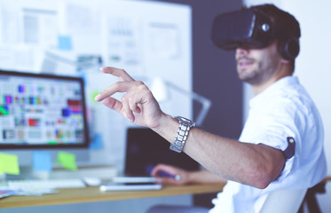 Young male software programmer testing a new app with 3d virtual reality glasses in office.